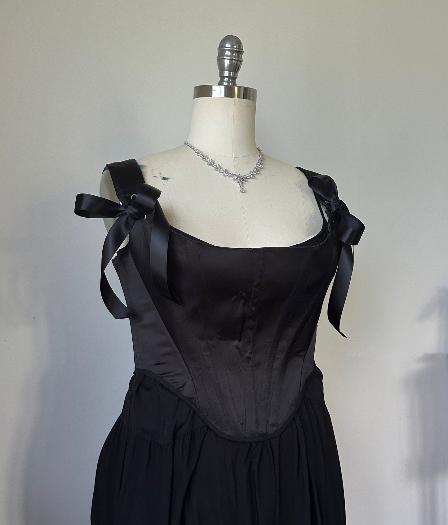 Black evening gown on a mannequin against a plain background